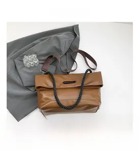 Detail view of brown leather tote bag with braided handle and adjustable shoulder strap