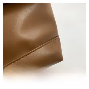 Close-up of the premium brown leather texture and precise stitching on the bag base
