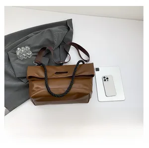 Detail of brown leather tote bag with unique fold-over closure and black braided handle