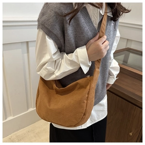 Dettaglio di una borsa hobo in pelle scamosciata marrone con tracolla larga a tracolla
