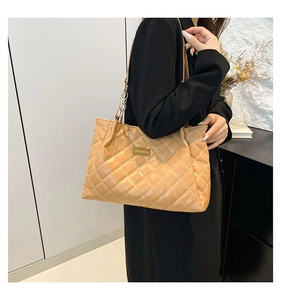 Detail of light brown quilted tote bag with gold chain strap and fashion label detail