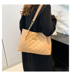 Detail of light brown quilted tote bag with gold metal hardware and wide shoulder strap