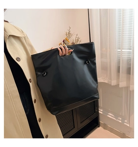 Grande borsa tote nera in pelle PU indossata da una modella con cappotto beige