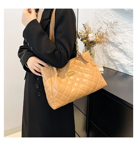 Detail of khaki quilted tote bag with chain strap shown in a modern interior setting