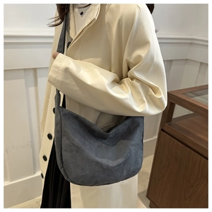 Dettaglio borsa a mezzaluna in camoscio grigio scuro indossata con un trench elegante