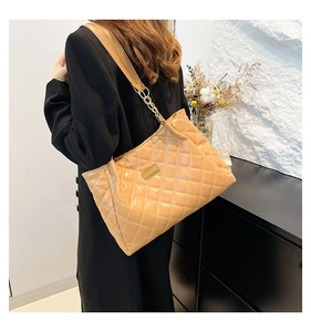 Close-up of quilted tote bag with gold chain strap and fashion metal plate detail