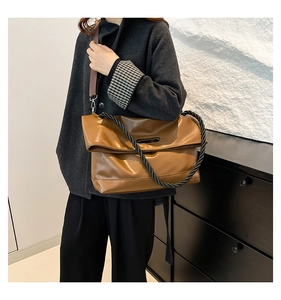 Brown tote bag with unique black braided rope handle and wide nylon strap shown on model