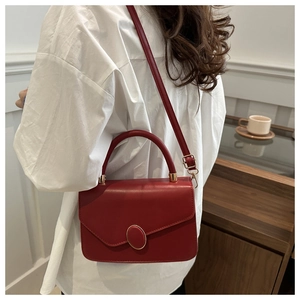 Borsa a mano rossa in pelle con fibbia ovale in metallo indossata da modella in ambiente chic