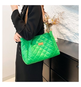 Detail of bright green quilted tote bag with chunky gold chain and fashion leather tag