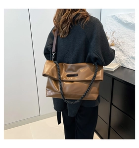 Brown leather tote bag featuring unique black rope straps and cutout handle design