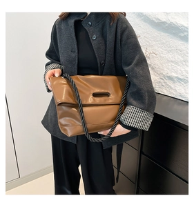 Dettaglio della borsa tote in pelle marrone con tracolla in corda nera e manico a incasso