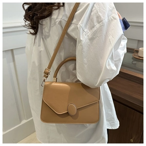 Dettaglio della borsa in pelle PU kaki con fibbia ovale e manico indossata dal modello