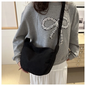 Modella che indossa una borsa a tracolla nera a mezzaluna con ampia tracolla in nylon