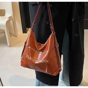 Détails du sac hobo marron vintage avec deux fermetures éclair dorées et texture en cuir