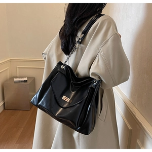 Detail of black PU leather tote bag with gold chain strap and metallic twist lock clasp