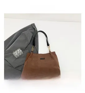 Détail du sac cabas en velours marron avec chaînes dorées et anses en cuir noir