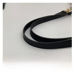 Détail de la bandoulière en cuir synthétique noir avec boucle en métal doré et chaîne