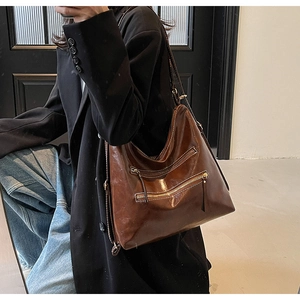 Détails du sac hobo en cuir marron vintage avec poches zippées et coutures contrastées