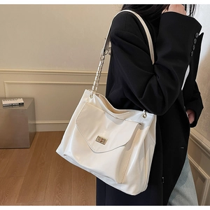 Close-up of white PU tote bag featuring a gold twist-lock and metal chain shoulder strap