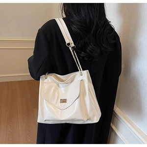 Back view of model wearing white large tote bag with glossy leather and chain strap