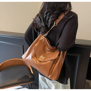 Détail du sac cabas en cuir marron avec fermoir rotatif doré et bandoulière chaîne