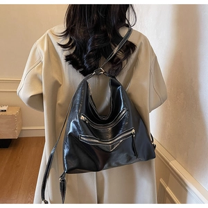 Gros plan du sac hobo en cuir brillant noir avec trois fermetures éclair et surpiqûres