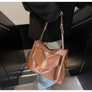 Detail of dark brown leather tote with golden twist lock and chain shoulder strap