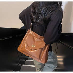 Detail of vintage brown PU leather tote with metal chain strap and twist lock pocket