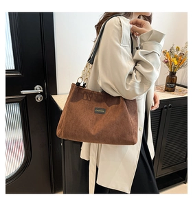 Détail du sac fourre-tout en velours côtelé marron avec bandoulière et écusson