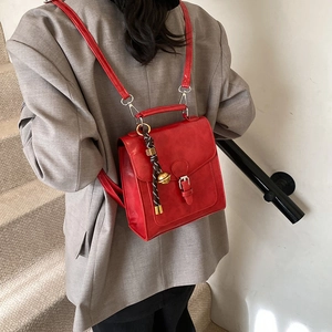 Retro red square backpack and handbag made of matte leather shown on model's shoulder