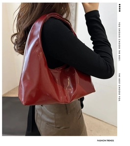 Close-up of a glossy red patent leather hobo bag with a sleek mirror-like finish