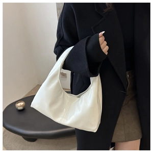 Close-up of a white patent leather hobo bag with high gloss finish on a model