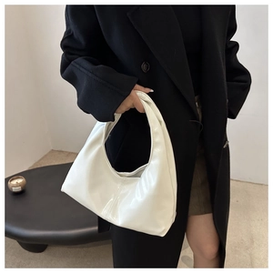 Detail of white glossy hobo bag with a sleek patent finish carried by a model
