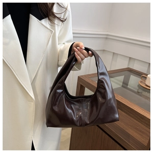 Detail of dark brown glossy patent leather hobo bag with elegant creased textures