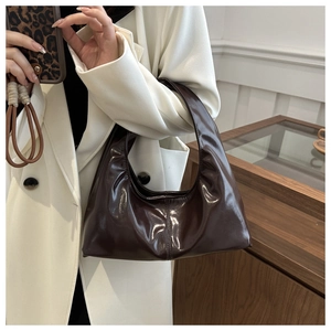 Detail of dark brown glossy leather hobo bag with vintage stitching and pleated texture
