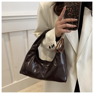 Detail of high-gloss brown faux leather hobo bag with elegant draped pleats for women