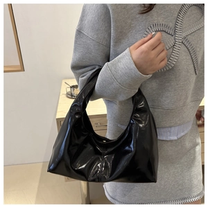 Detail of glossy black patent leather hobo bag with smooth finish and hobo curve