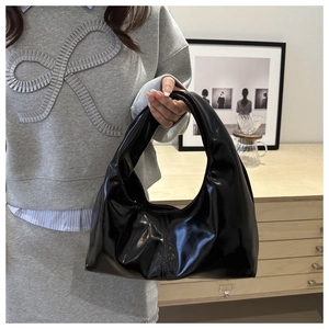 Glossy black crescent bag shown in a minimalist interior setting for daily fashion