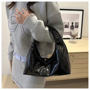 Detail of glossy black patent leather hobo bag with sleek moon shape and zipper closure