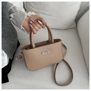 Detail of khaki leather handbag with silver logo on a white couch background