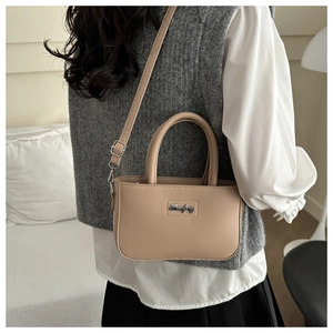 Close-up of a beige mini square crossbody bag with silver hardware and top handle