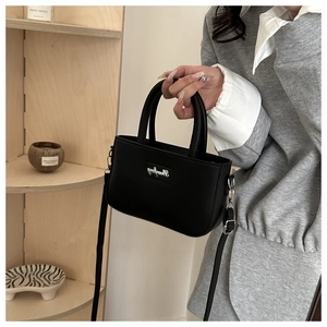 Detail view of a black faux leather crossbody bag with silver hardware and top handles