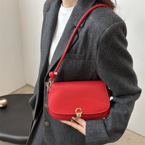 Chic red saddle shoulder bag with gold hardware worn over a grey wool blazer