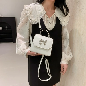 Mini sac carré blanc avec boucle nœud argenté porté par un mannequin avec style