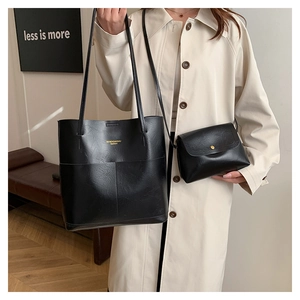 Detail view of large black tote and crossbody bag set worn with a beige trench coat