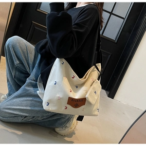 Detail of canvas tote bag with colorful letter embroidery and adjustable black shoulder strap