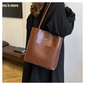 Detail shot of a brown large-capacity tote bag showing the textured faux leather and strap
