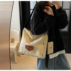Detail view of beige canvas tote with colorful embroidery and small pouch for women