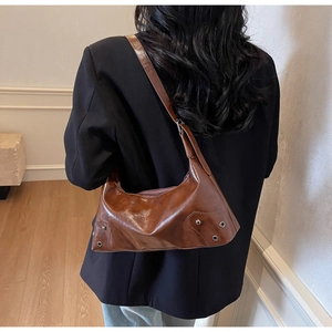 Detail of vintage brown oil wax leather hobo bag with silver rivet accents on shoulder