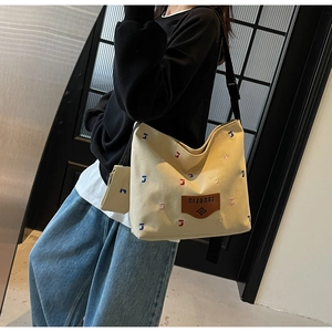 Macro detail of canvas tote bag with colorful letter embroidery and logo patch